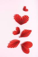 Beautiful composition of folded red paper hearts and leaves on a pink background  vertical view photo