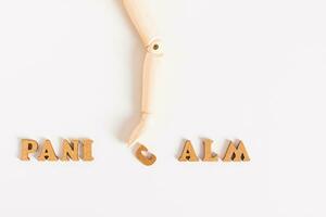 Panic calm concept wooden hand moves letter on light background photo