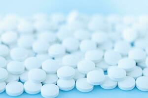 White pills on blue background, medicine background photo