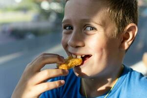 A boy with a pleasant smile enjoys eating delicious nuggets photo