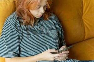 Social Media Interaction,Red Haired Teen Girl Using Smartphone on Couch for Chat and Video photo