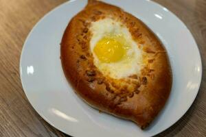 auténtico khachapuri, tradicional georgiano huevo y queso pan, desplegado a un acogedor café foto