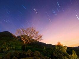 Night Sky with Star Trails over Tranquil Mountain Landscape photo