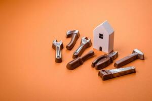 Repair or home improvement tools and a house model on a plain background photo