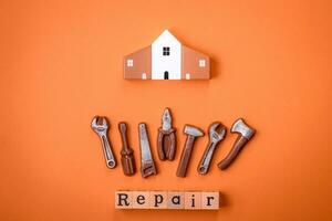 Repair or home improvement tools and a house model on a plain background photo