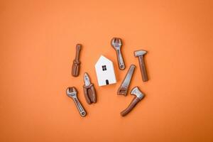 Repair or home improvement tools and a house model on a plain background photo