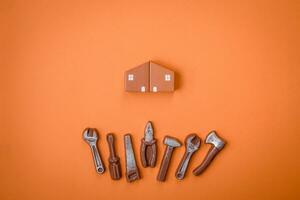 Repair or home improvement tools and a house model on a plain background photo