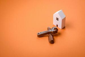 Repair or home improvement tools and a house model on a plain background photo