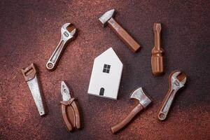 Repair or home improvement tools and a house model on a plain background photo