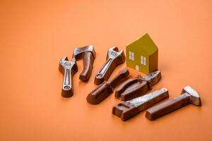 Repair or home improvement tools and a house model on a plain background photo