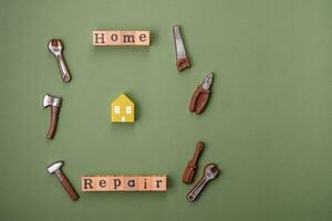 Repair or home improvement tools and a house model on a plain background photo