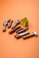 Repair or home improvement tools and a house model on a plain background photo