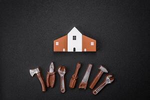 Repair or home improvement tools and a house model on a plain background photo