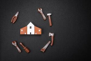 Repair or home improvement tools and a house model on a plain background photo