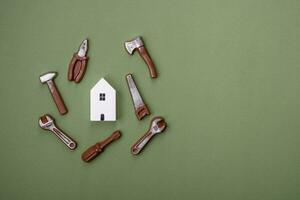 Repair or home improvement tools and a house model on a plain background photo