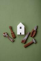 Repair or home improvement tools and a house model on a plain background photo