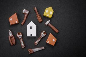 Repair or home improvement tools and a house model on a plain background photo