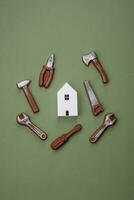 Repair or home improvement tools and a house model on a plain background photo