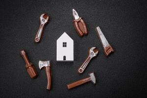 Repair or home improvement tools and a house model on a plain background photo