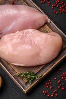 Fresh chicken fillet on a dark concrete table with spices and herbs photo