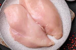 Fresh chicken fillet on a dark concrete table with spices and herbs photo