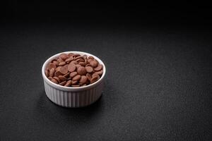 Round granules of sweet confectionery chocolate as an ingredient for preparing desserts photo