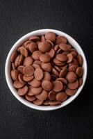 Round granules of sweet confectionery chocolate as an ingredient for preparing desserts photo