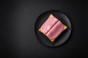 Delicious sandwich with toast bread, ham, tomatoes, salt and spices photo