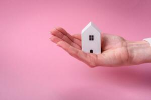 Female hands, a small wooden house and keys as an idea for investing in your own home and achieving the goal of buying real estate photo