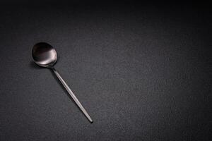 Empty metal spoon on dark textured concrete background photo