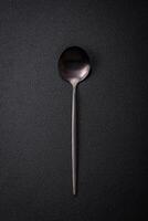 Empty metal spoon on dark textured concrete background photo