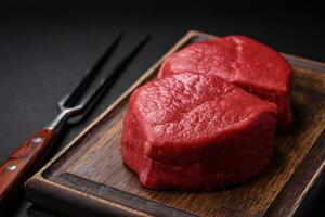 Fresh juicy raw filet mignon with salt, spices and herbs photo