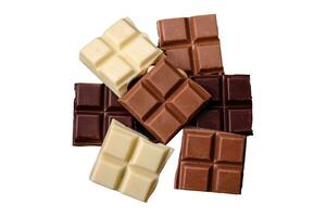 A mix of several types of delicious sweet chocolate broken into cubes on a black plate photo