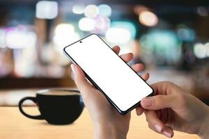 Smartphone mockup in hands with coffee mug on table, creating a cozy coffee time reading news concept. Perfect for showcasing digital content in a relaxed setting photo