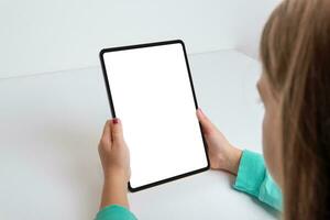 Vertical tablet held by a girl on a work desk. Perfect for showcasing games or apps with an isolated screen. Modern technology in the hands of a young user photo