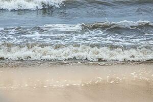 the waves of the cold sea near the sandy beach. no one. photo