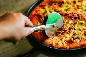 Cutting pepperoni pizza into slices with a pizza cutting special knife. photo