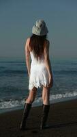 irreconocible sensualidad hembra en pie en negro arenoso playa, relajación verano playa Días festivos video