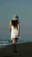 Sensuality unrecognizable female walking along black sandy beach during summer beach holidays video