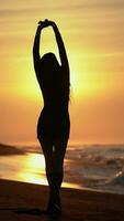 femme avec mains élevé en marchant et tournant autour sur sablonneux plage à lever du soleil pendant plage vacances video