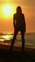 Slim woman with long legs moving and turning around on sandy beach at sunrise. Female in short dress video