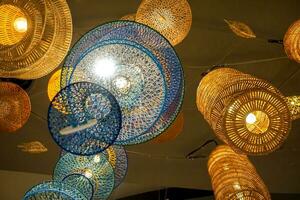 Lookup view and closeup decorative wicker lantern hang on hotel lobby ceiling background with open lights on photo