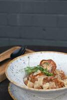 Bolognese in a bowl on a dark background decoration with dry tomato and microgreen photo