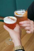 dos alcohólico cócteles en manos terminado un de madera cafetería mesa. foto
