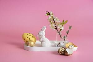 White rabbit, blossom twig and Easter eggs on a pink background. Easter composition photo