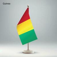 Flag of Guinea hanging on a flag stand. vector