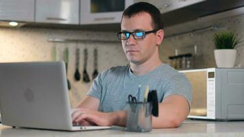 Man freelancer, Stay at home, online working, self isolation, surfing web, distant job. Male student uses online technology from home sitting in the kitchen using laptop video