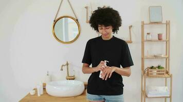 pelle cura, cosmetici a casa, naturale crema, terme trattamenti, misto gara. afro americano donna l'applicazione crema per sua mani e sorridente a telecamera video