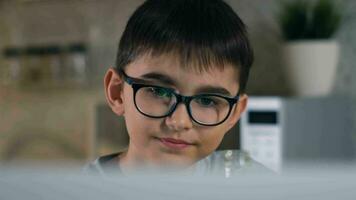 Stay at home, leisure at home, technologies for children, self isolation. A cheerful boy in glasses is watching his favorite cartoons while sitting at home using a laptop and drinking soda. video