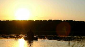 fiske på hav, fiskare i en båt, fiske under solnedgång, aktiva resten. en man i en båt flyter av de kust under solnedgång. tillbaka se video